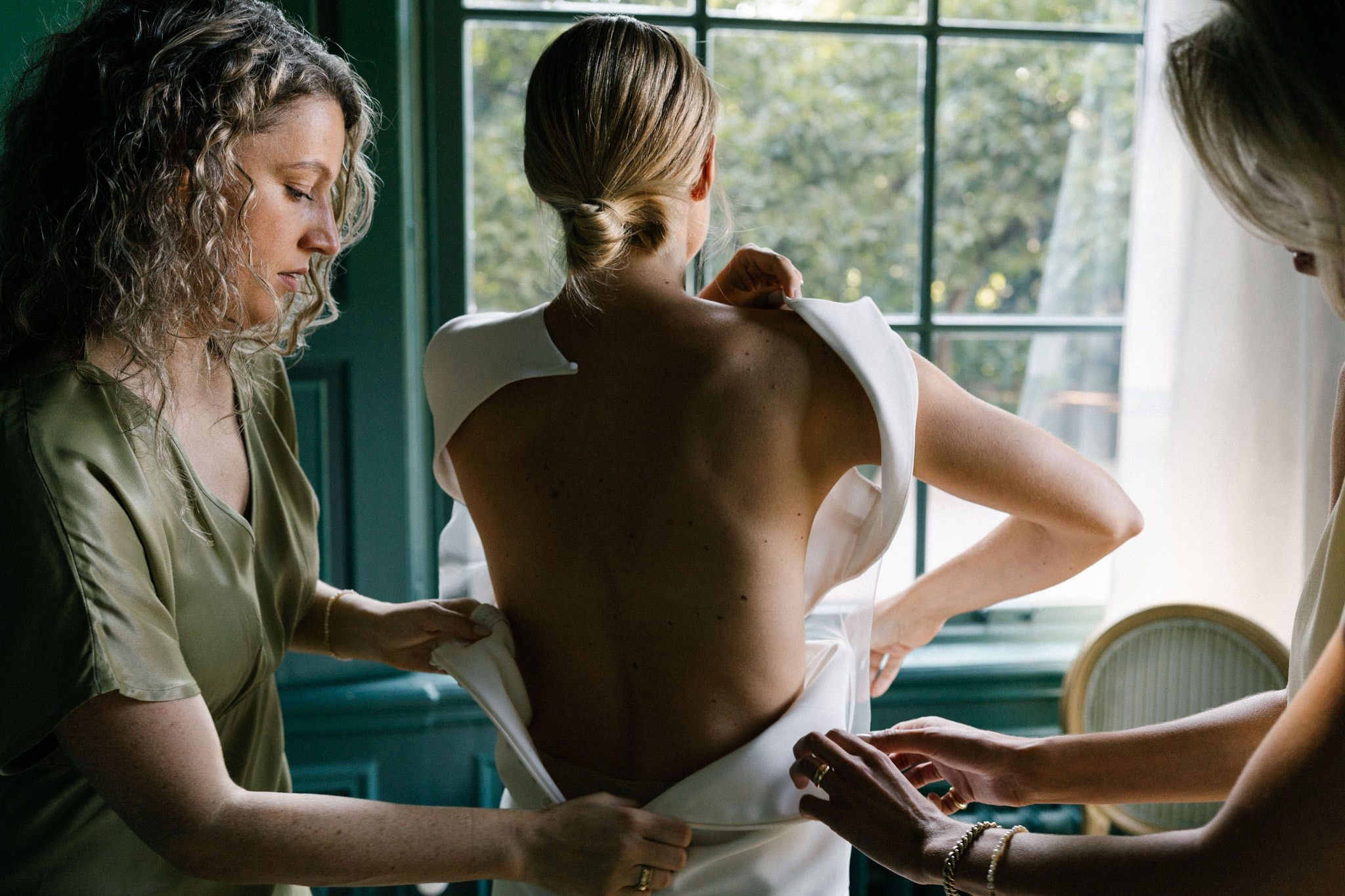 Bride with friends helping her dress